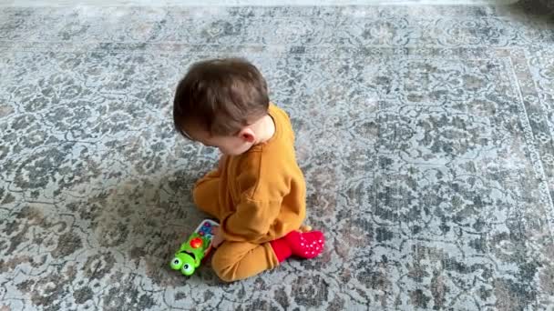장난감 전화와 바닥에 오렌지 수트에 아이가 장난감에 버튼을 누릅니다 — 비디오
