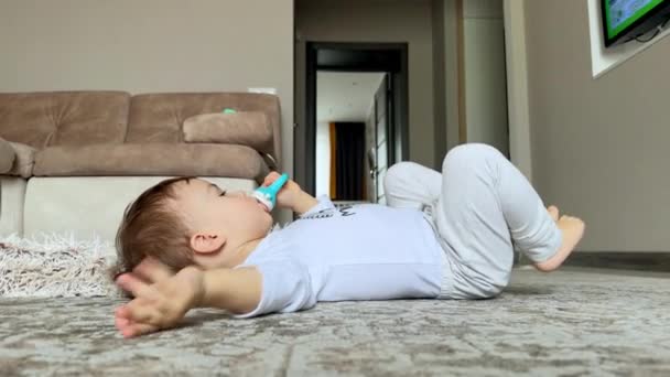Niño Con Ropa Blanca Yace Suelo Sosteniendo Chupete Pacifico Bebé — Vídeos de Stock