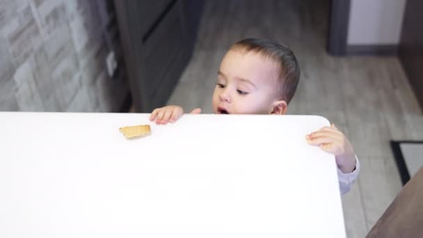 漂亮的孩子走到桌前 婴儿伸出手去从桌上拿饼干 小孩吃了点东西就走了 顶部视图 — 图库视频影像