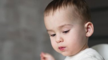 Beyaz bir bebeğin melek gibi tatlı bir yüzü var. Küçük çocuk kameraya dilini gösteriyor. Kapatın. Bulanık arkaplan.