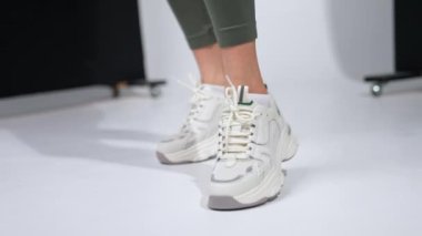 Tozlu ve rahat spor ayakkabılı kadın. Stüdyoda şık spor ayakkabıları. Bulanık arkaplan.