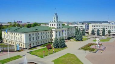 Güneşli bir günde güzel Ukrayna şehrinin üzerinde yükseliyor. Devletin bayrakları ve ağaçlarla birlikte yerleşim alanları olan harika bir hükümet binası. Üst görünüm.