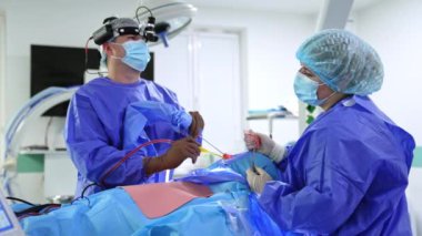 Burun ameliyatında modern aletleri uygulayan güvenilir otolaringoloji uzmanı. Doktor işlem sırasında monitöre bakar. Bayan hemşire asistanı..