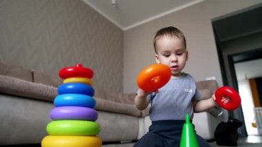 Küçük Kafkas bebek piramidi inşa ediyor. Çocuk yüzükleri yanlış dizmiş. Düşük açı görünümü.