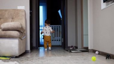 Neşeli erkek bebek odadan odaya koşuyor. Mutlu çocuk gülüyor ve evinde oynuyor..