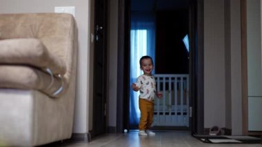 Mutlu beyaz çocuk ev hakkında heyecanlı bir şekilde koşuyor. Evde yeni yürüyen bir çocuk için oyun zamanı.