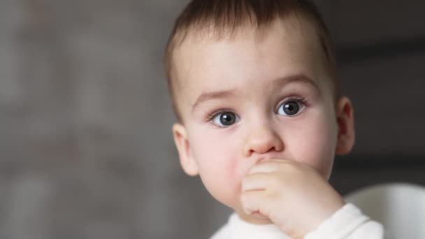 一个漂亮的白人男婴把东西送到嘴边的脸近照孩子们吃东西的肖像 模糊的背景 — 图库视频影像