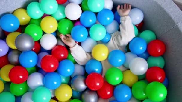 Oğlan Kuru Bir Havuzda Renkli Topların Içinde Saklanıyor Yürümeye Başlayan — Stok video