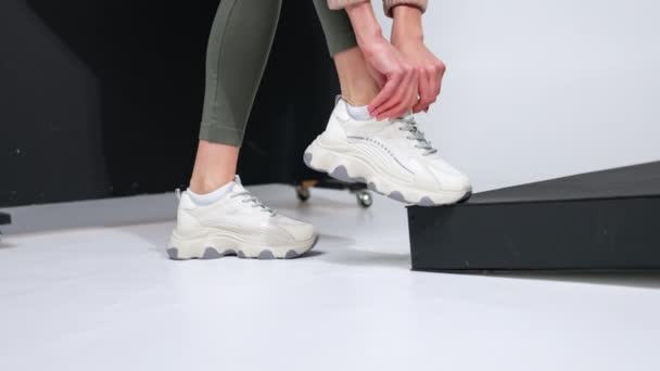 模特儿正配她时髦漂亮的白色运动鞋 在演播室展示时尚舒适的鞋子 — 图库视频影像