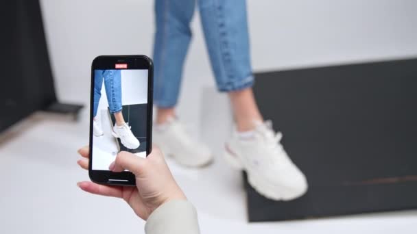 拍摄了一个女孩展示现代运动鞋的手机视频 演播室里时髦的休闲装 — 图库视频影像