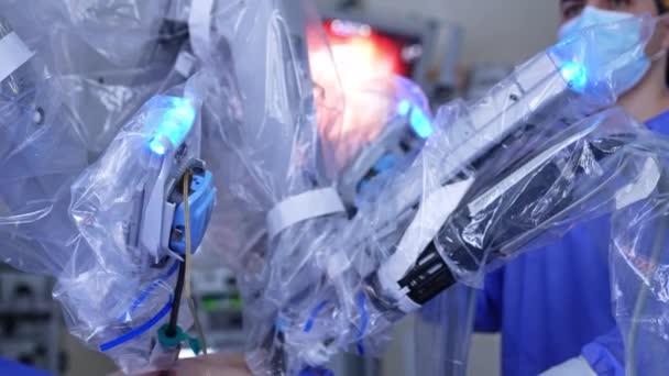 プラスチック製の動きで覆われたロボットアームは 患者の腹部の最小限の削減に入力されています クローズアップ バックドロップの医師 — ストック動画