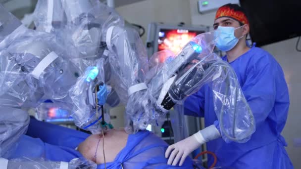 ヴィンチ ロボット システムは腹腔鏡検査を行っている 外科医は装置の近くに立っており スクリーンで動作を監視します — ストック動画