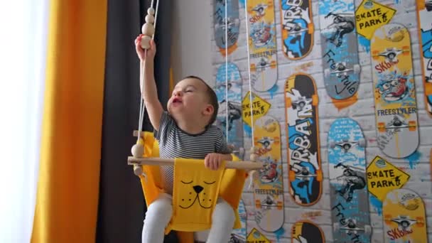 Little Boy Swings Yellow Swing Indoors Kid Plays Wooden Beads — Stock Video