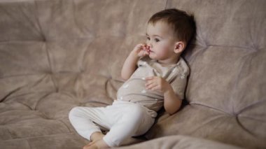 Güzel beyaz çocuk büyük kanepede dinleniyor. Aktif oyunlardan sonra bebek dinleniyor.