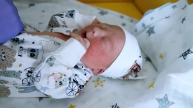 Eldivenli eller bebeğin şortunun düğmelerini bağlıyor. Yeni doğan çocuk ağlamaya başlar. Kapat..