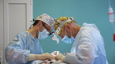 Farları olan iki doktor ameliyathanede iş birliği yapıyor. Erkek doktorlar tiroidektomi yaparlar..