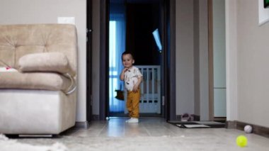 Kapıda bekleyen sevimli erkek bebek. Sevimli küçük çocuk gülümseyerek odaya dalıyor..