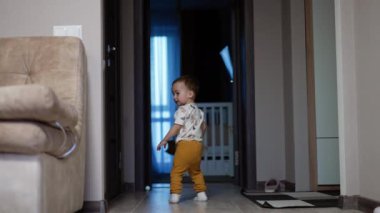 Evin etrafında koşan sağlıklı, aktif, beyaz bir çocuk. Gülümseyen bebek evde oynuyor..