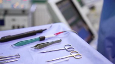 Ameliyat odasındaki masada cerrahi makas, pens ve elektrikli tıbbi aletler var. Kapatın. Bulanık arkaplan.