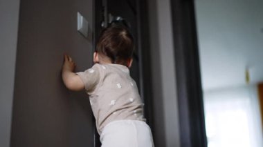 Kapının önünde duran bir çocuğun dikiz aynasından. Çocuk karanlık bir odanın kapısını açar ve bir şey arar. Düşük açı görünümü.