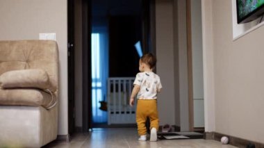 Mutlu çocuk evde neşeyle oynuyor. Anne oğluna elini uzatır ve o da gülerek kaçar..
