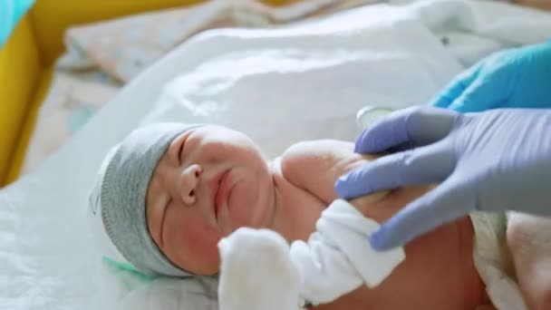 神経科医は赤ちゃんの心臓を聞いています 少年は検査に不満を抱いている クローズアップ — ストック動画