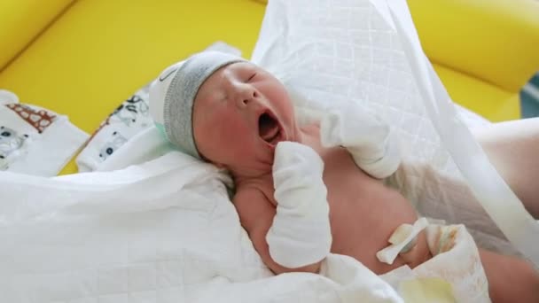 帽子とミトンで生まれた小さな赤ちゃん ラップの中の子供は手に取られています クローズアップ — ストック動画