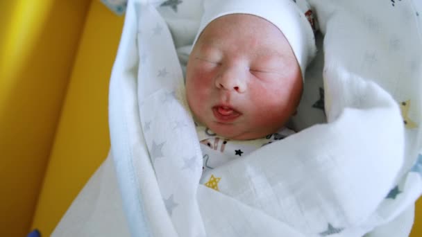 毛布で覆われたかわいい新生児の睡眠 美しい子供は光からウィンクしています クローズアップ — ストック動画