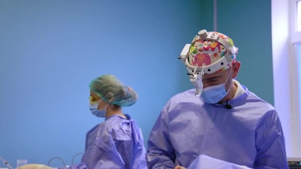冷静严肃的外科医生在手术室里做手术 护士在后台准备工具 — 图库视频影像