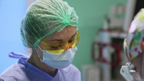 Женщина Врач Маске Колпаке Желтых Защитных Очках Помогающих Операции Закрыть — стоковое видео