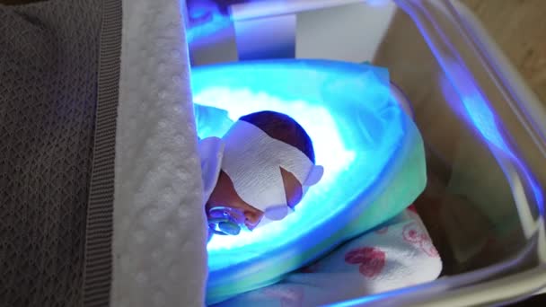 婴儿在医院的婴儿床上积极地哺乳着奶嘴 用光疗治疗新生儿黄疸 — 图库视频影像