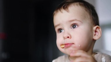 Tatlı çocuk ağzına bir parça kurabiye sıkıştırmış. Yeni yürümeye başlayan çocuk, elinde bir sonraki yiyeceği muz olduğu için bisküviyi çiğnemeye çalışıyor. Kapatın. Bulanık arkaplan.