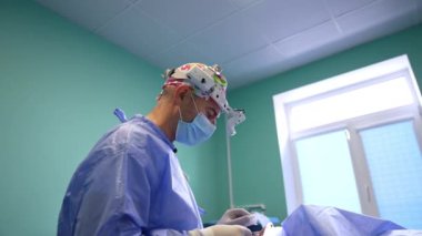 Profesyonel cerrah göz kapağı ameliyatında. Farlı doktor eliyle hareket eden kamerayla konuşuyor. Düşük açı görünümü.