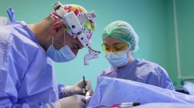 Farları takan deneyimli bir cerrah tarafından yapılan göz kapağı ameliyatı. Sarı gözlüklü doktor yardım ediyor..
