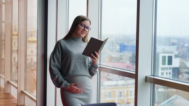 Positiv Lächelnde Schwangere Mit Brille Liest Ein Buch Lady Steht — Stockvideo