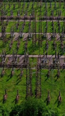 Yeşil alanlar arasında elektrik desteği. Yüksek voltajlı çelik direklerle büyük bir alanın üzerinden uçuyorlar. Doğadaki yüksek voltaj hatları. Hava görüntüsü. Dikey video