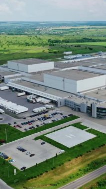 Doğada büyük bir üretim alanı. Yeşil alanların ortasındaki endüstriyel fabrikanın panoramik görüntüsü. Hava görüntüsü. Dikey video