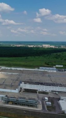 Tarlalardaki sanayi bölgesinin panoramik görüntüsü. Kırsal alanda yeşil arka planda modern fabrikanın geniş bir bölgesi. Hava görüntüsü. Dikey video