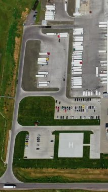 Sahada sanayi bölgesi var. Yukarıdan birçok otoparkı olan modern bir imalatın çatılarına bakın. Hava görüntüsü. Ağır çekim. Dikey video