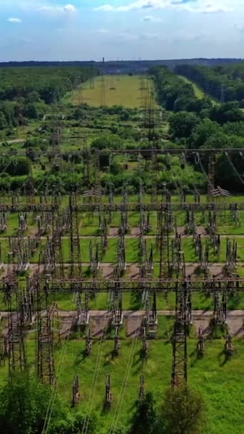 グリーンフィールドの高圧鋼ピロン 送電線の上からの眺め 自然の中にある電気塔 空からの眺め バーティカルビデオ — ストック動画