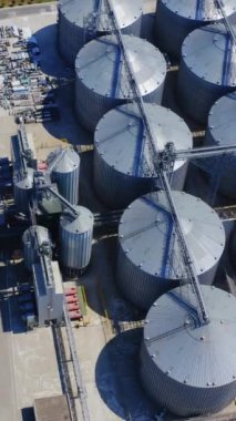 Metal asansörler sahada. Tahıl depolamak için tahıl ambarı. Alüminyum kaplar sahada. Endüstriyel bölgede yük vagonları. Üst hava manzarası. Dikey video