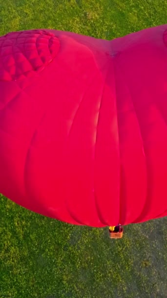空気中の大きな空気スタット 田舎を飛んでいる心臓の形をした美しい赤い熱気球 人々は夏に飛行船のバスケットで旅行する クローズアップ バーティカルビデオ — ストック動画