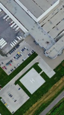 Fabrika yeşil alanda. Endüstriyel bölgeden ve yakınlardaki birçok arabadan görüntüyü alın. Beyaz kamyonlar park yerinde. Hava görüntüsü. Dikey video