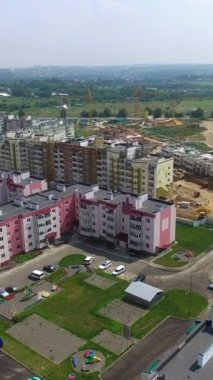 Yazın yeni yerleşim yerinin üzerinde uçuyor. Yeni bölgede inşa edilen modern binaların panoramik üst görüntüsü. Hava görünümü Dikey video