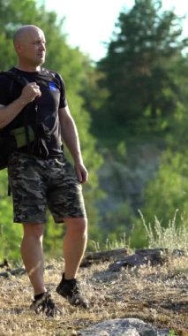 Siyah tişörtlü ve şortlu tüysüz turist bu güzel manzaraya hayran ve gezisine devam ediyor. Yaz aylarında sırt çantasıyla gezen genç gezgin. Dikey video