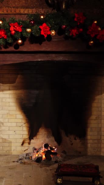 お祝い 居心地の良い暖炉 暖炉の近くの新年のデザイン背景 快適なマントルで部屋の中のクリスマスの装飾 暖かい家の気分 バーティカルビデオ — ストック動画