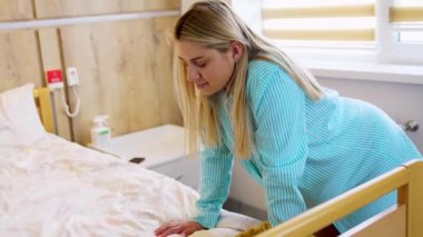 Bayanın doğum öncesi kasılmadan dolayı ağrı hissetmesini bekliyorum. Kadın yatağa eğiliyor ve yavaşça nefes alıyor..