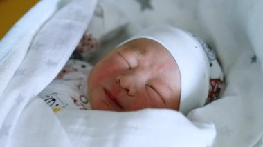 Sevimli yeni doğmuş beyaz çocuk uyanıyor ve surat asıyor. Bebek bir gözünü açar ve tekrar uykuya dalar. Kapat..