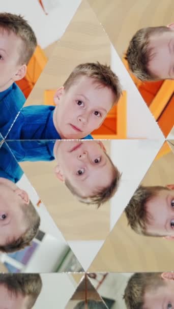 好奇的男孩穿着蓝色和黄色的衬衫 在万花筒的镜子里反射出来 摘要儿童在万花筒的许多三角形部分的蒙太奇 垂直录像 — 图库视频影像