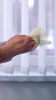 Beyaz önlük giyen erkek doktor beyaz lateks eldiven giyiyor. Kapatın. Hastanedeki doktor koruması. Dikey video